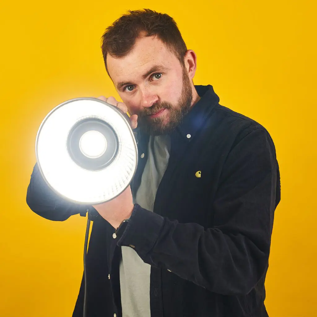 Bull & Wolf Joe headshot, yellow background holding a spotlight