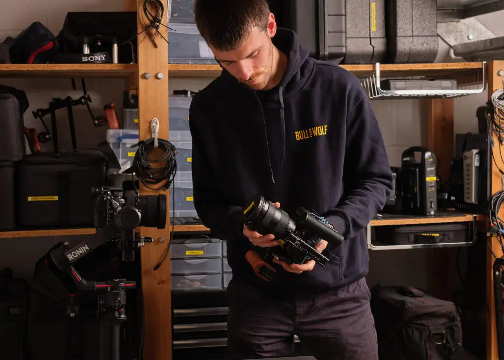 Man in B&W hoodie taking lense off a camera