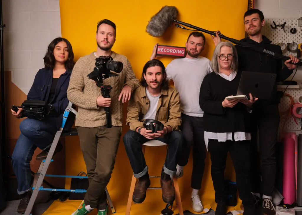 Bull and wolf team stood in front of yellow background looking at camera