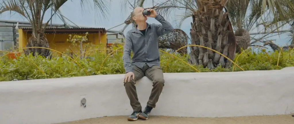 Man without barista drinking reusable cup on wall