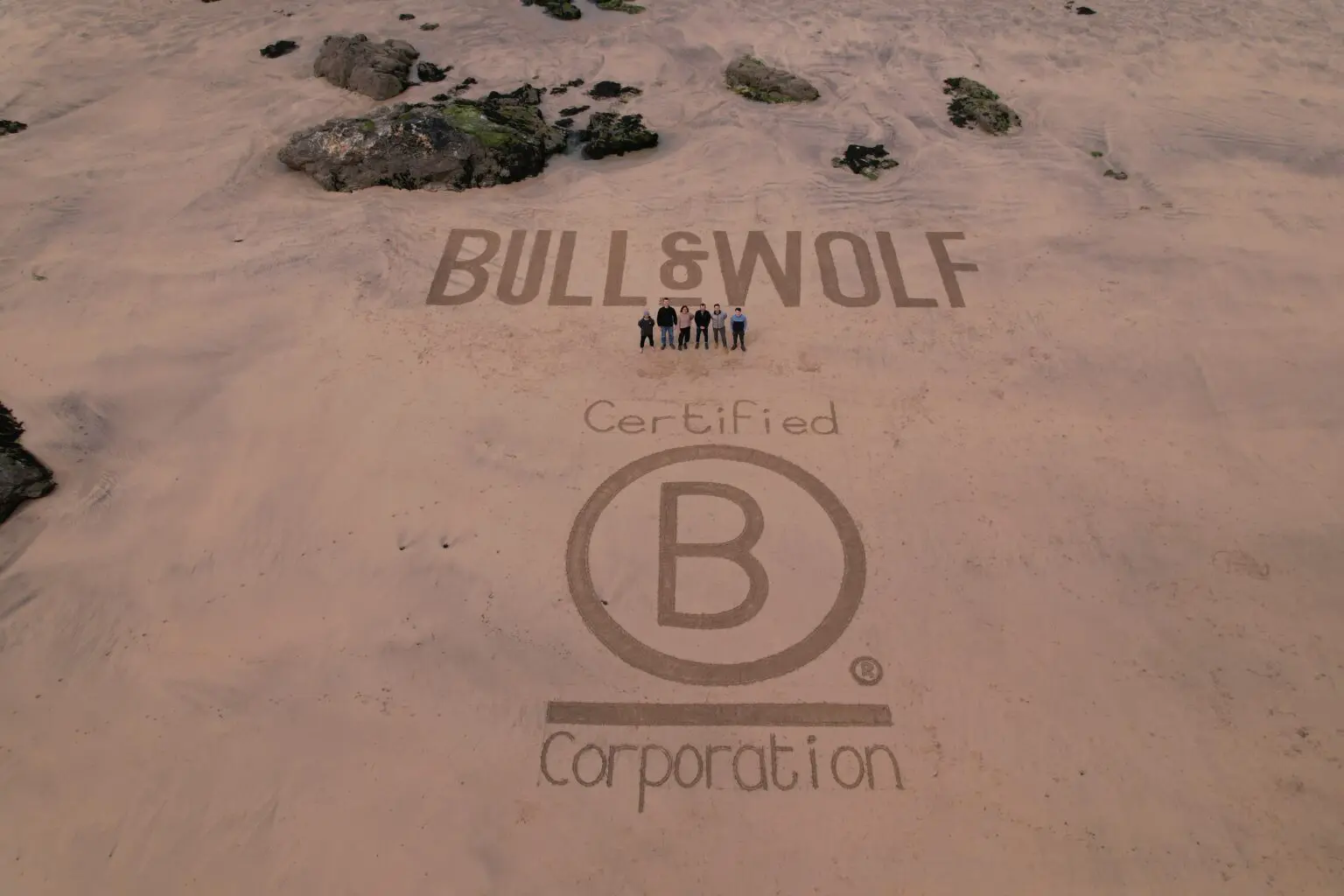 Beach with 'Bull & Wolf B Corp Certified' written in the sand