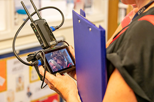 Woman holding a clipboard and a camera, watching footage back on the screen