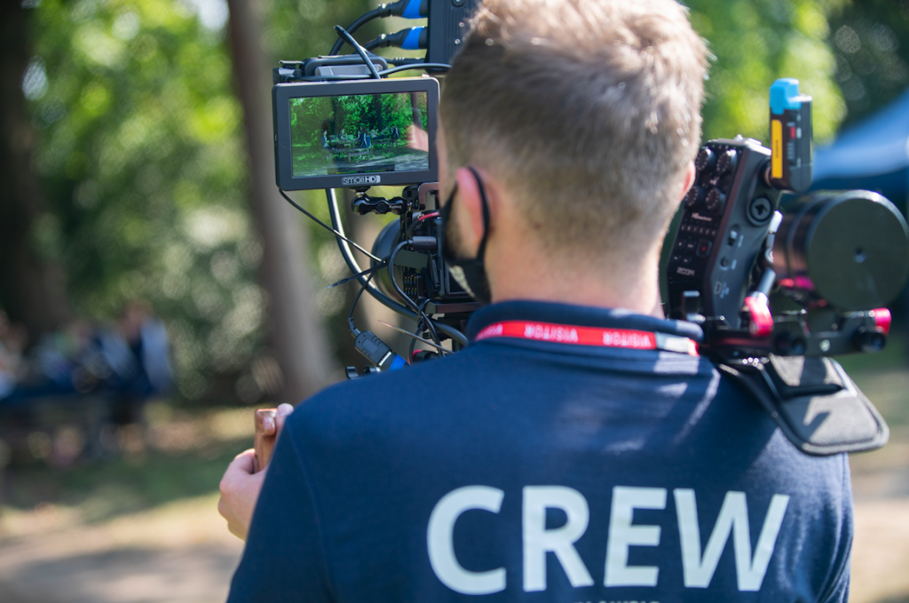 Back of a Bull & Wolf camera man in crew tshirt with camera on shoulder