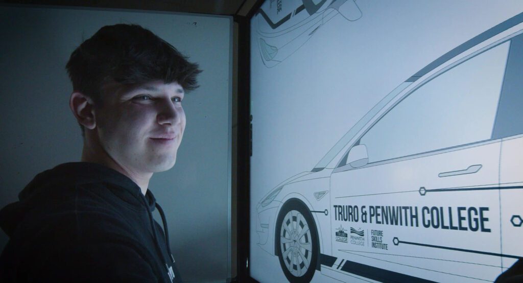 Boy with short black hair looking at large screen with car diagram and Truro & Penwith branding design