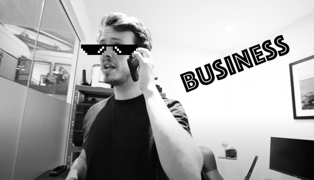 Black and white image of a man on the phone with emoji glasses and 'business' written on side