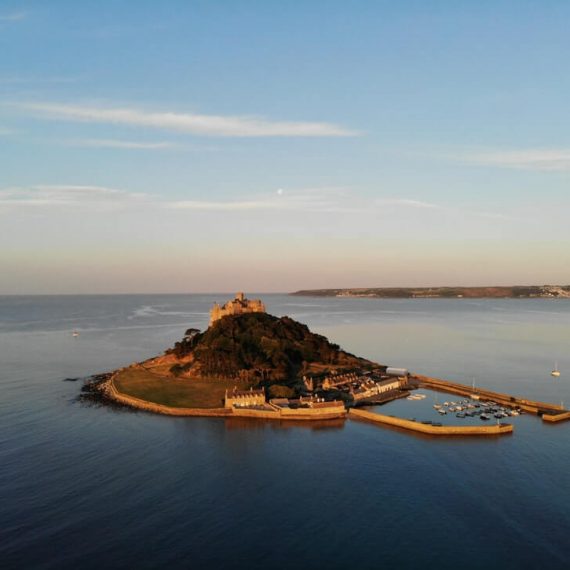 drone shot of island with castle sat in the middle of open waters