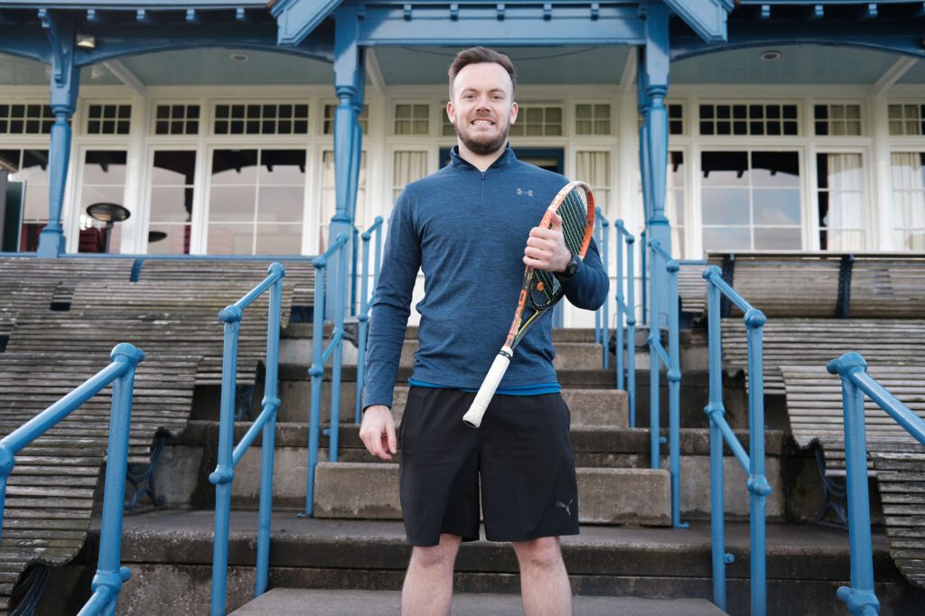 Man on steps with tennis racket