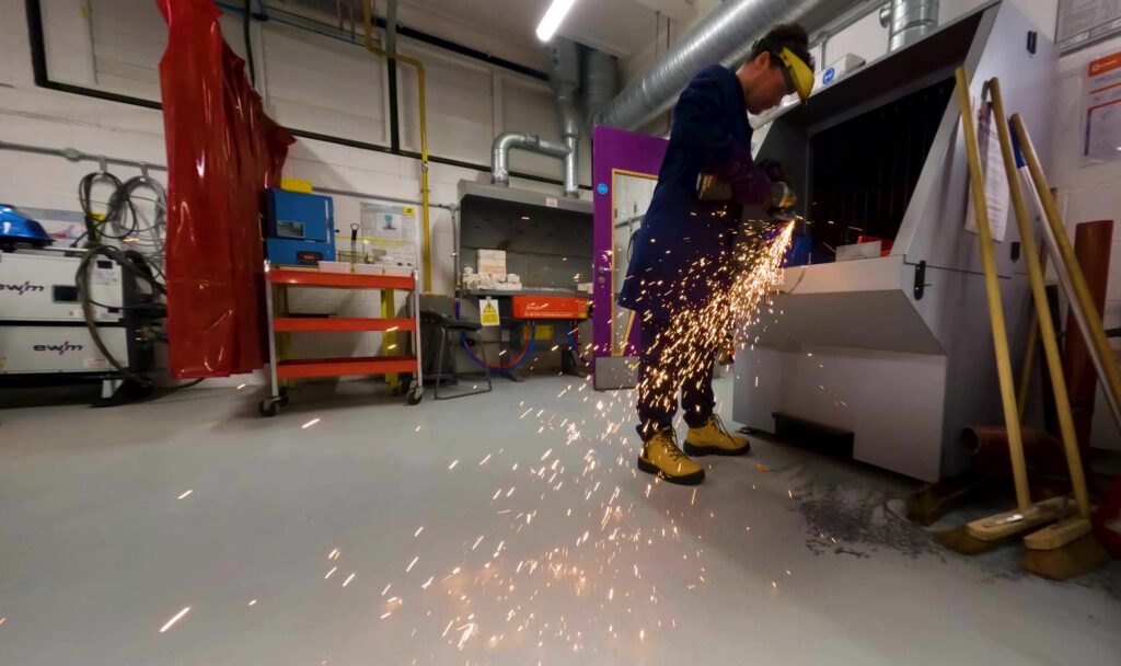 Man stood grinding in workshop with sparks flying